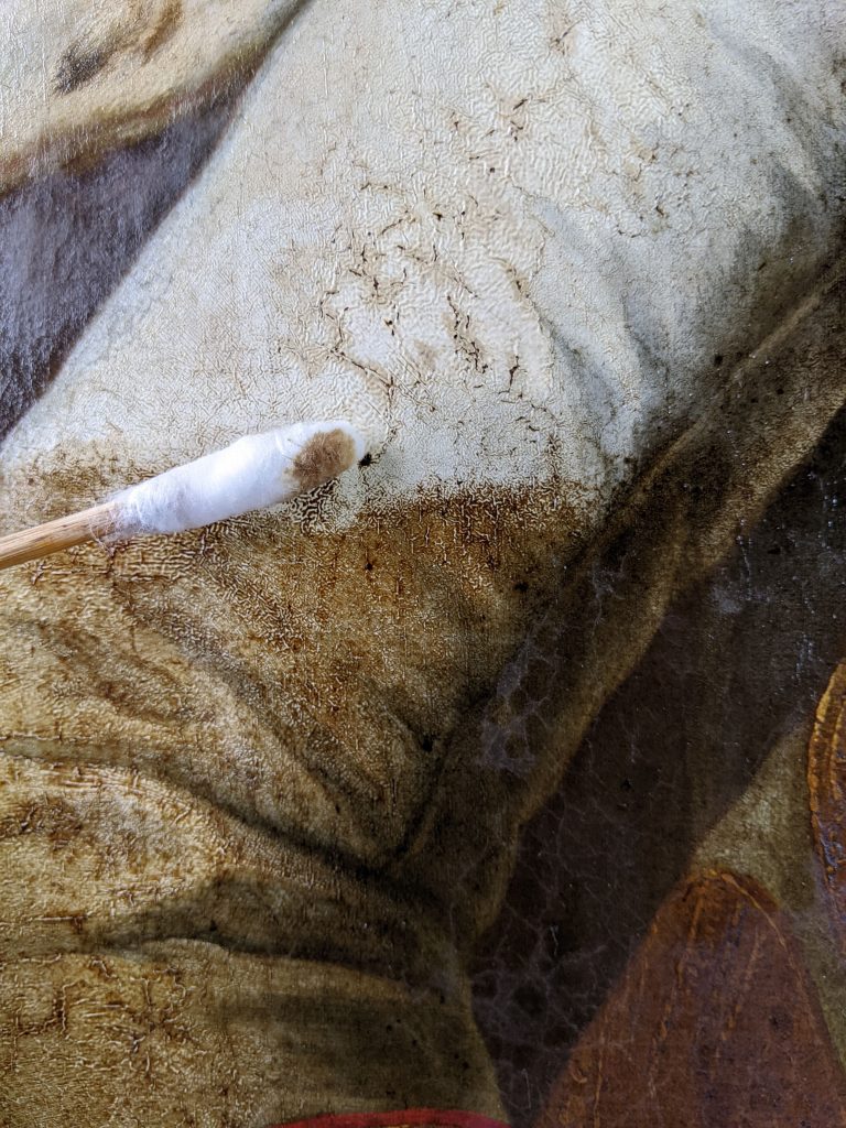 Détail du nettoyage: le vernis trés encrassé et oxydé est retiré, dévoilant le costume blanc